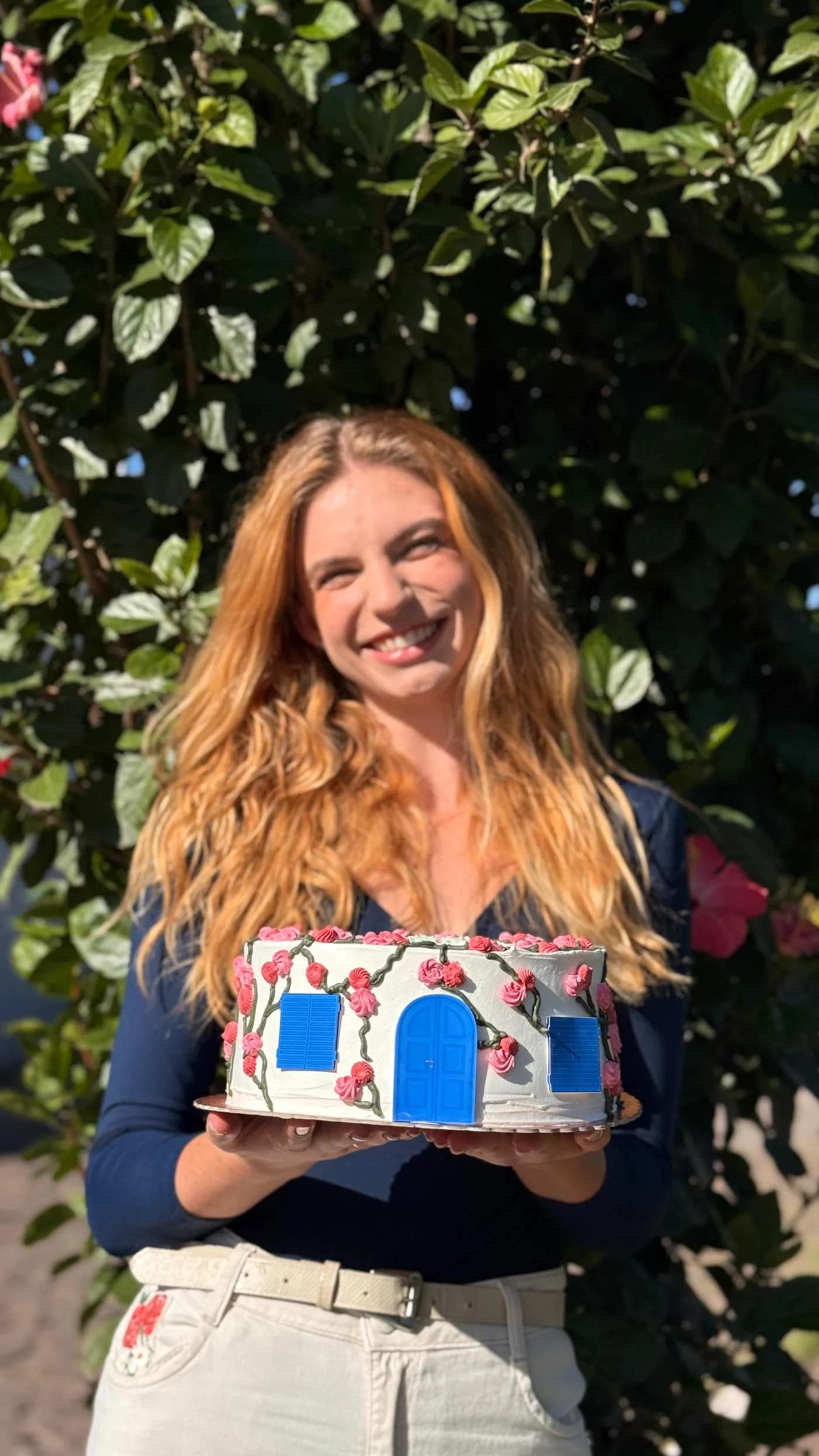 Alice Becker sorrindo ao ar livre com um bolo
